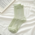 Calcetines verde menta con textura de canalé sobre fondo de tela blanca elegante - Verde