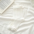 Minimalist cream-white mid-calf cotton socks shown on a clean white fabric background - Bleached White
