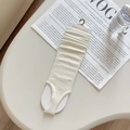 Cream knit stirrup leg warmers with vertical ribbed texture on product card packaging - White
