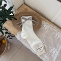White hollow mesh knit socks with floral bow and wavy cuffs in a rustic setting - One Size / White