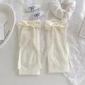 Lolita style cream white sheer socks with elegant oversized satin bows on white background - Bowknot