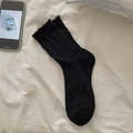 Sweet black mid-calf socks with ruffle trim and ribbed texture in a lifestyle setting - One Size / Black