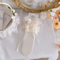 Calze a rete bianche con balze in pizzo e fiocco in raso su supporto decorativo - Taglia unica / Beige