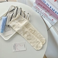 Beige knit socks with ruffled edges and bow patterns displayed on a tray - One Size / Beige
