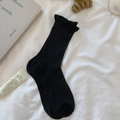 Black cotton mid-calf socks with sweet ruffle trim and ribbed texture in home setting - One Size / Black