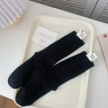 Minimalist black crew socks with ribbed knit texture and paper tag in a lifestyle setting - One Size / Black