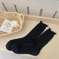 Calcetines de punto negros para mujer con bordes ondulados sobre fondo madera - Talla única / Negro