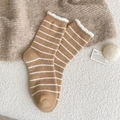 Calze pelose a righe bianche e marroni con volant esposte su una coperta di maglia - Marrone
