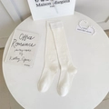 Minimalist cream beige knee high socks with ribbed texture in a lifestyle setting - One Size / White