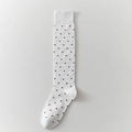 Classic white knee-high socks featuring black polka dots and elastic ribbed cuffs - White