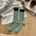 Grass green wool socks with black rib-knit cuff on a warm wooden background - One Size / Army Green