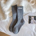 Mid-calf dark gray ribbed socks with white fabric label on cozy white plush background - One Size / Dark Gray