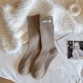 Brown rib-knit mid-calf socks with white cloth label detail on cozy wool mat - One Size / Brown