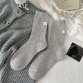 Grijze gespikkelde wollen sokken met Hello-label en gekleurde gebreide stippen in minimalist - Eén maat / donkergrijs