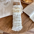 Witte gebreide beenwarmers met kant en strik op een rustieke houten ondergrond - Crèmewit / Verticaal Geribbelder