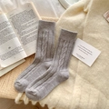 Dicke graue Wollsocken mit Zopfmuster im Vintage-Stil in einem rustikalen Korb - Hellgrau