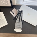 Grey knit leg warmers with black silk bow ribbons in a minimalist study desk setting - Gray