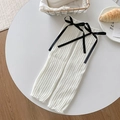 Jambières blanches en tricot avec nœuds en satin noir dans un décor chaleureux - Base Blanche Noeud Noir