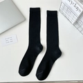 Minimalist black ribbed calf socks in breathable cotton blend laid flat on white desk - Black Thin Ribbed Long