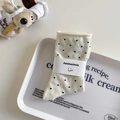 Creamy white crew socks with black polka dots and rolled edges on a white tray - White