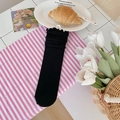 Japanese style black cotton crew socks with ruffled lace trim on striped background - Black