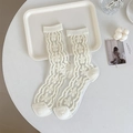Weiße transparente Netzsocken mit Blumenstickerei und Wellentextur auf einem Tablett - Beige