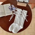 Witte Lolita kniekousen met gekruiste linten en strikken op een donkerhouten tafel - Eén maat / Wit