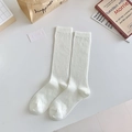 White waffle textured crew socks in a cozy minimalist aesthetic display on a desk - Small Grid Pattern