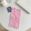 Pink Tabi socks with vertical ribbed knit texture shown on a minimalist white desk - One Size / Deep Pink