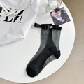 Sheer black mesh socks with satin bow and rhinestone embellishment in 45-degree view - One Size / All Black