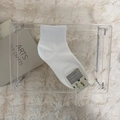 White crew knit socks with ribbed cuffs and botanical tag on plush white carpet - One Size / White