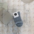 Folded grey knit crew socks with minimalist tag on a soft white faux fur background - One Size / Gray