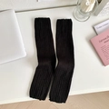 Classic black ribbed knit leg warmers in a stylish flat lay lifestyle arrangement - One Size / Black