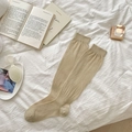 Beige rib-knit knee high socks in Japanese ballet style on white bedding - Green