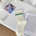 Calze bianche con strisce verdi e toppa smiley in un ambiente minimalista - Strisce Verdi