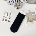 Black Japanese style mesh slouch crew socks with elegant rolled cuffs on white desk - One Size / Black