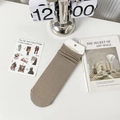 Brown crew socks with vertical rib texture and paper tag on a minimalist desk - One Size / Coffee