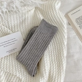 Hellgraue Thermosocken mit vertikalen Rippen auf einer weichen weißen Strickdecke - Hellgrau