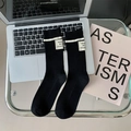 Schwarze gerippte Wollsocken mit weißen Streifen und Vintage-Etikett auf dem Tisch - Schwarz