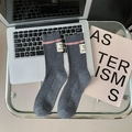 Graue Wollsocken mit rosa Streifen und Webetiketten auf einem modernen Schreibtisch - Grau