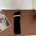 Classic black ribbed knit calf-high socks with branded label on a wooden surface - Black