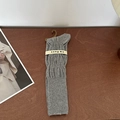 Dark grey ribbed knit knee-high socks with branded paper wrap on wooden background - Gray