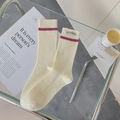 Beige cashmere socks with red stripe and fabric label in a cozy home setting - One Size / Creamy White