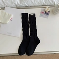 Solid black slouch socks with white label featuring vertical ribbed knit texture - One Size / Black