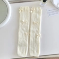 Jambières en tricot crème avec côtes verticales et nœuds doux sur fond blanc épuré - Beige