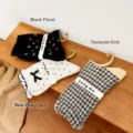 Detailweergave van vintage sokken met bloemen- en stippenpatroon op houten standaard - Zwart Bloemen / Zwart