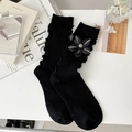 Black crew socks with ruffled edges and side flower ribbon bow in a lifestyle setting - One Size / Black