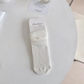 Calze bianche a coste stile balletto con trama morbida e cartellino su un tavolo bianco - Taglia unica / Bianco