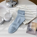 Light blue crew sock with dark blue embroidery and ribbed cuff on a minimalist desk - One Size / Sky Blue