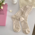 Beige hollow knit Lolita socks in retro style shown with elegant aesthetic props - Khaki